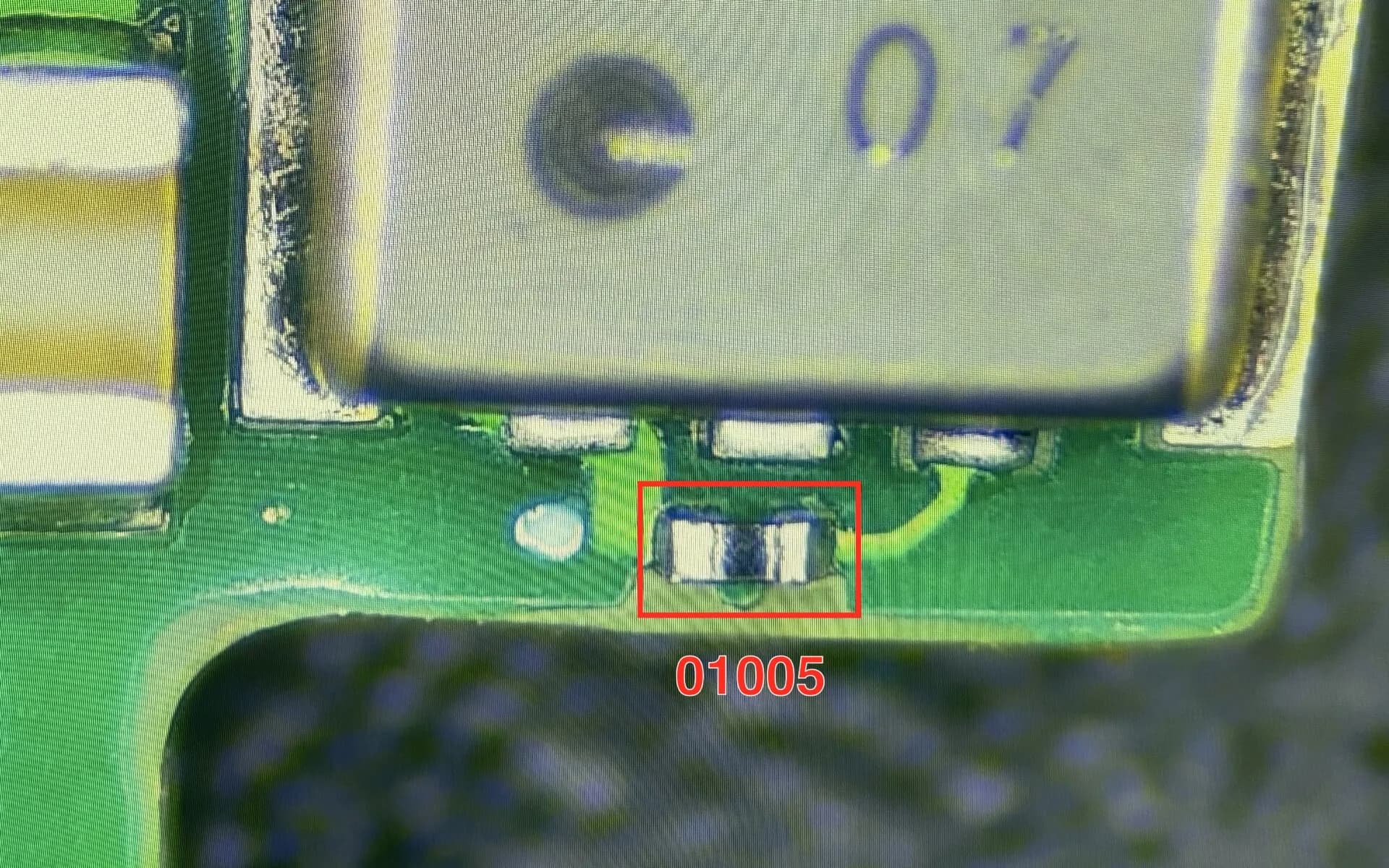 Componente 01005 colocado e soldado numa placa de produção, visto ao microscópio